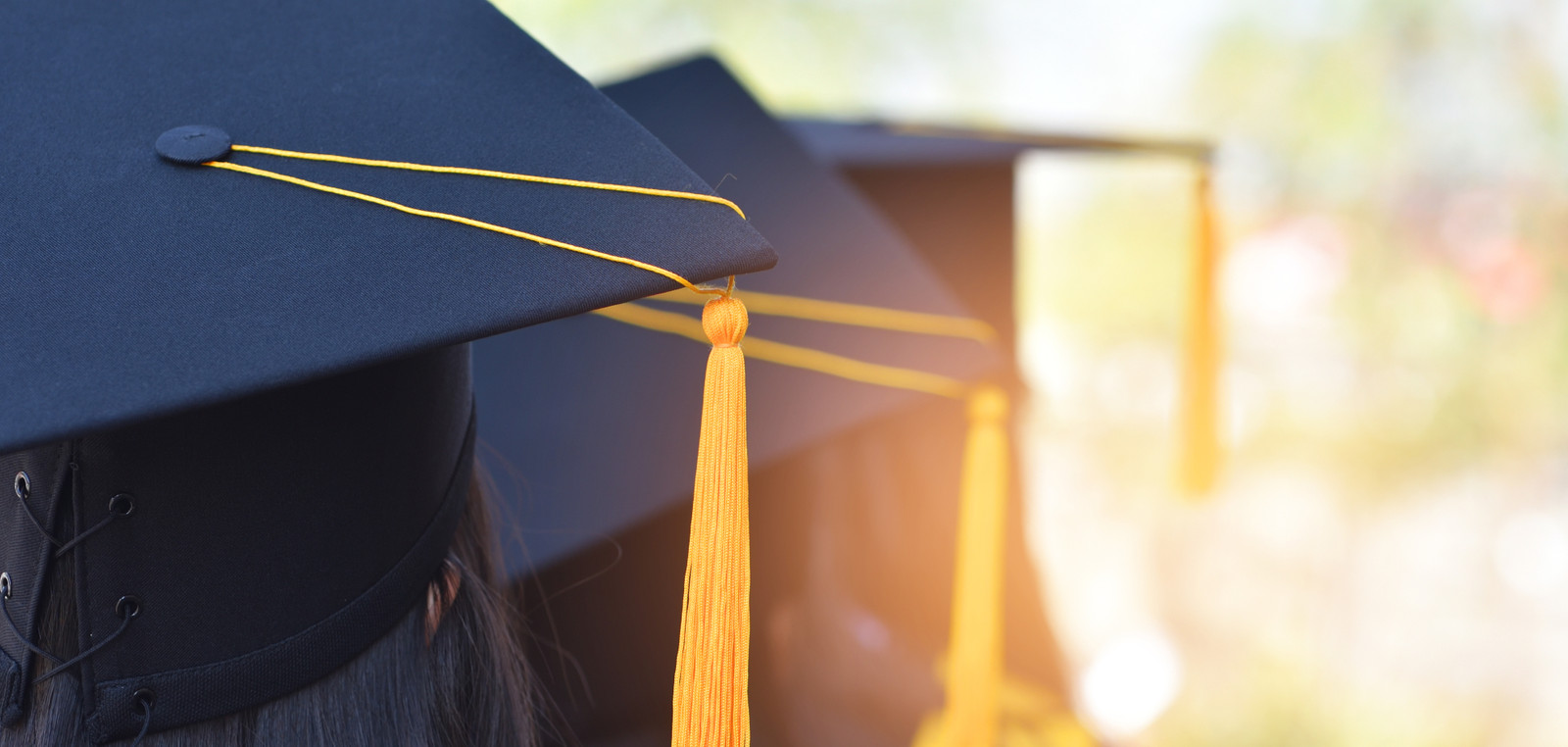 Back image graduates wearing yellow tassel hat