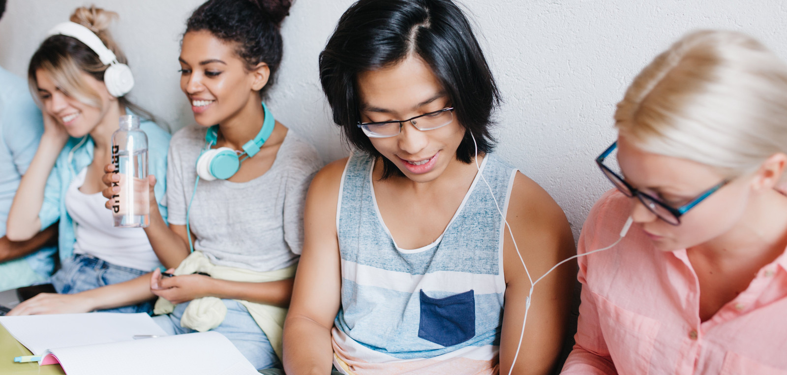 Diverse students using mobile with headphone